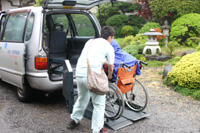 小雨の中、利用者さんを車から降ろす河野さん