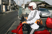 相棒の赤いバイクにまたがって利用者さん宅を訪問する山崎さん。